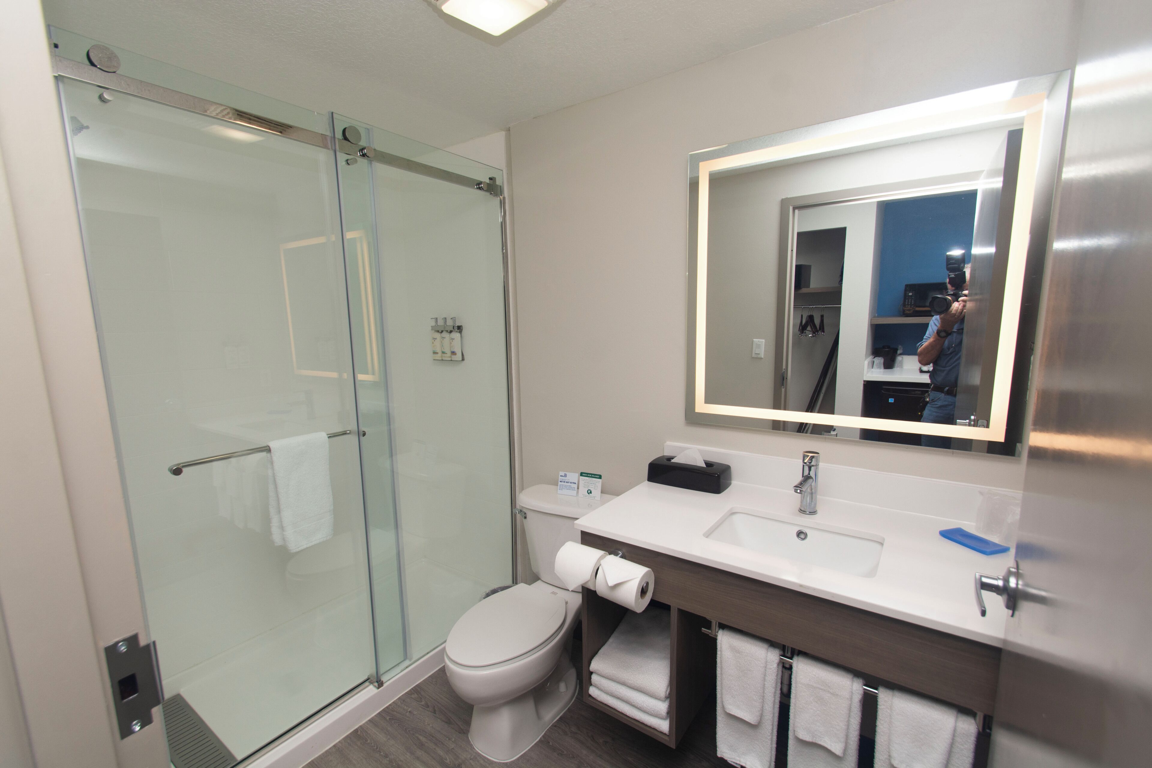 A modern bathroom with a glass shower enclosure, a toilet, a sink with a mirror, and a towel rack.
