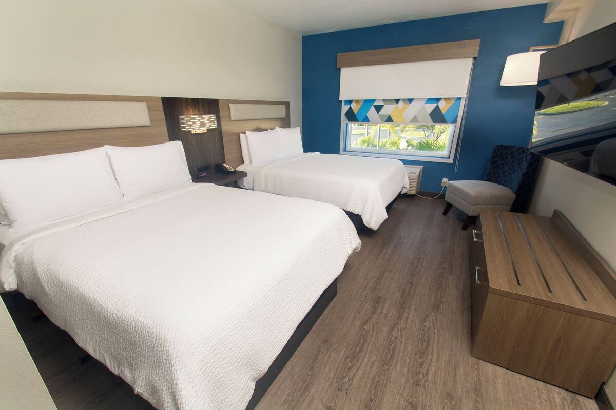 Une chambre d’hôtel avec deux lits, un bureau et une fenêtre donnant sur un beau paysage.