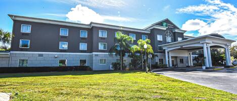 A large hotel with multiple floors, a covered entrance, and a well-maintained lawn.