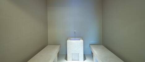 Un baño moderno con un lavamanos central, bancos a cada lado y luces empotradas en el techo.