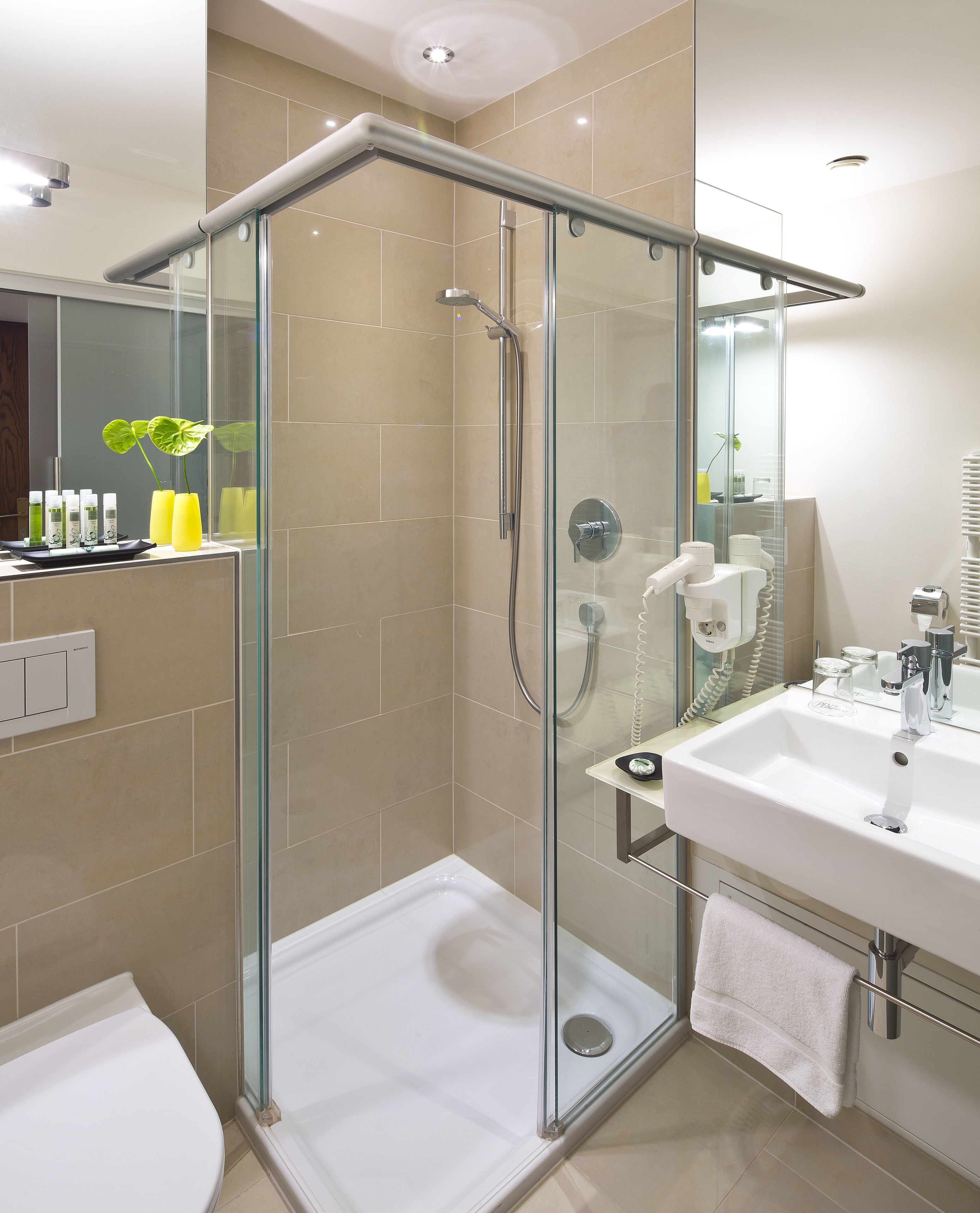 A modern bathroom with a glass-enclosed shower, a white sink, and a mirror above the sink.