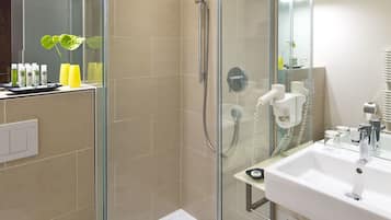 A modern bathroom with a glass-enclosed shower, a white sink, and a mirror above the sink.