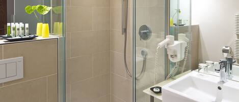 A modern bathroom with a glass-enclosed shower, a white sink, and a mirror above the sink.