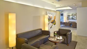 A modern lobby with a sofa, armchairs, a coffee table, and artwork on the walls.