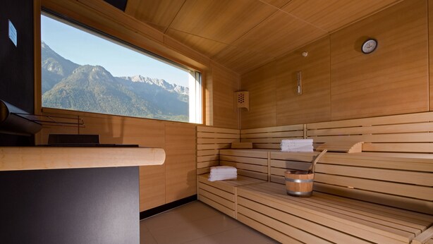 Un sauna con bancos de madera, una ventana con vistas a la montaña y un perchero para toallas.