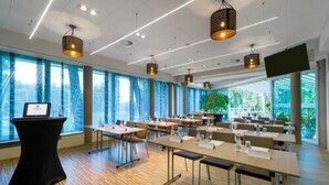 Un salón de conferencias con largas mesas, sillas y un atril.