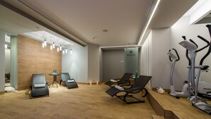 Un moderno centro de bienestar con equipo de ejercicio, sillas de relajación y piso de madera.