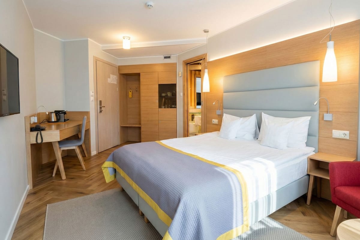 Una habitación de hotel con cama, escritorio, silla y televisión.