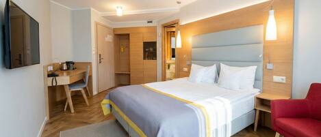 Una habitación de hotel con cama, escritorio, silla y televisión.