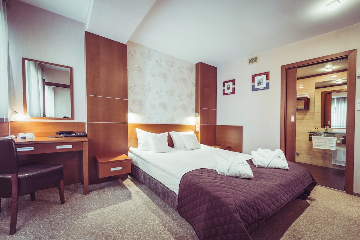 Habitación de hotel con cama, escritorio, silla y espejo.