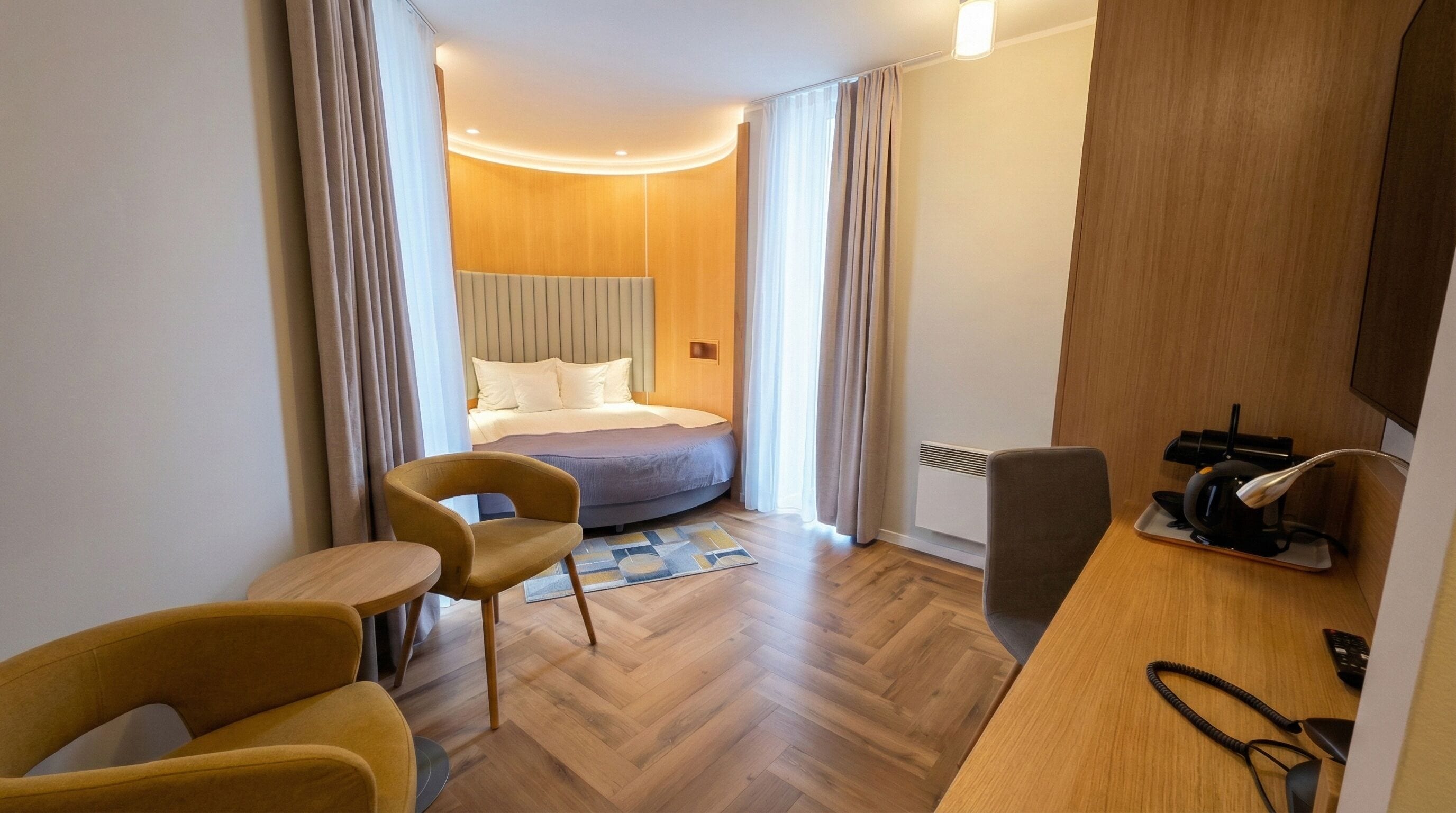 A hotel room with a bed, a desk, a chair, and a small table.