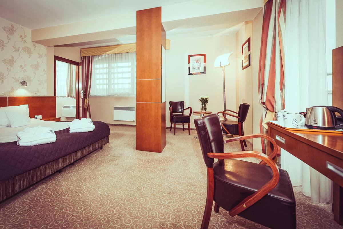 Una habitación de hotel con cama, escritorio, silla y un gran pilar.