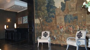Un vestíbul amb un mural, dues cadires, una recepció i un llum penjant a la paret.