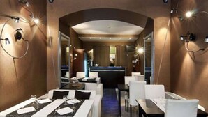 Un restaurant modern amb una barra central, taules blanques i il·luminació ambiental.
