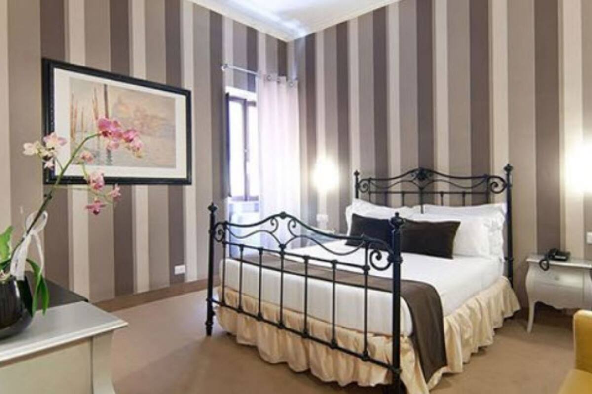 Ein Hotelzimmer mit Bett, Nachttisch, Sessel und einem gerahmten Bild an der Wand.