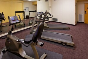 Une salle de sport équipée de tapis de course, d’un vélo elliptique et d’un vélo d’appartement.