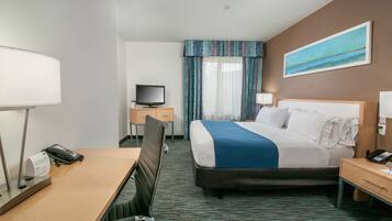 A hotel room with a bed, desk, chair, television, and a painting on the wall.