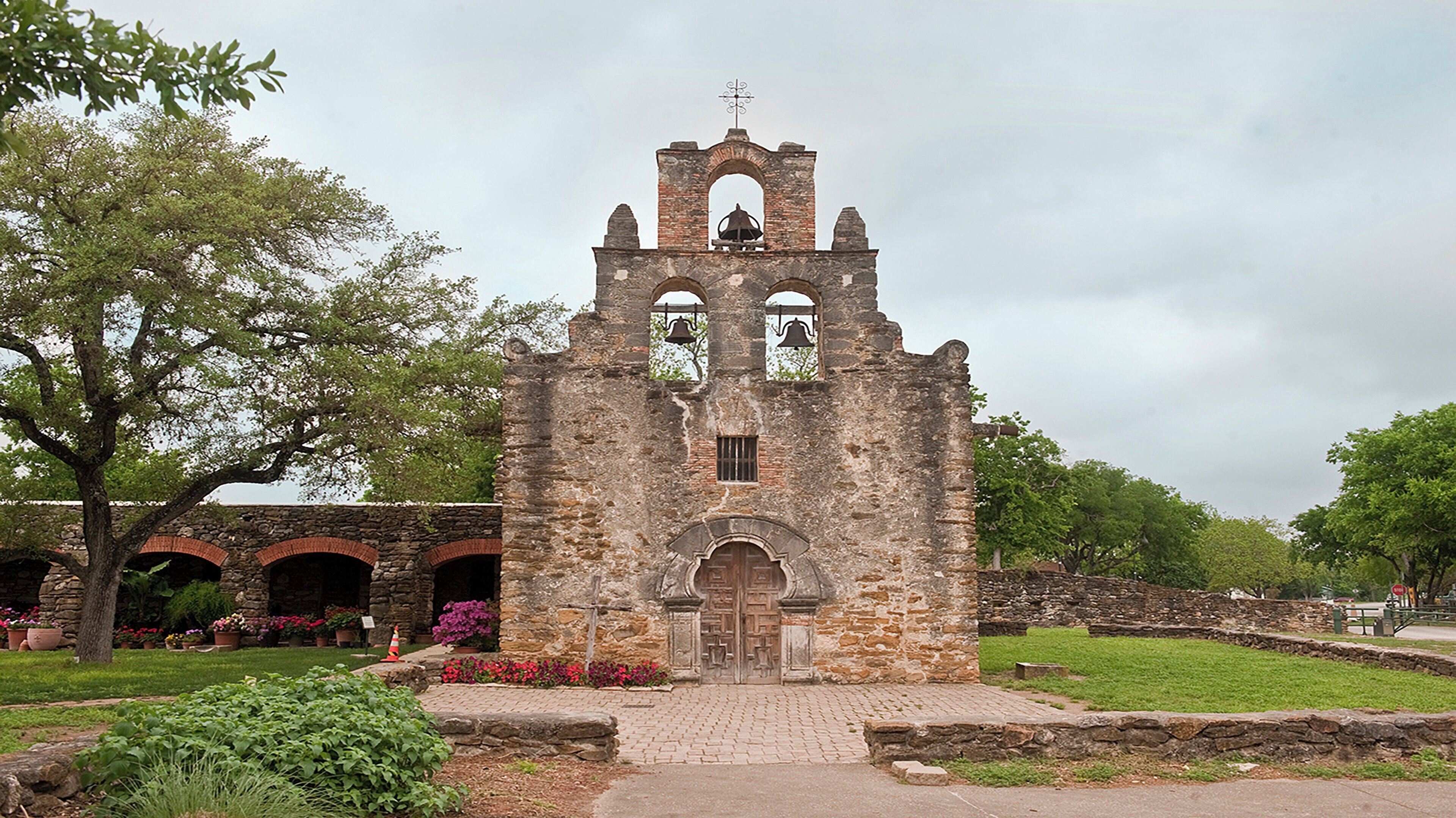 An old stone church with a bell tower, arched windows, and a central door.