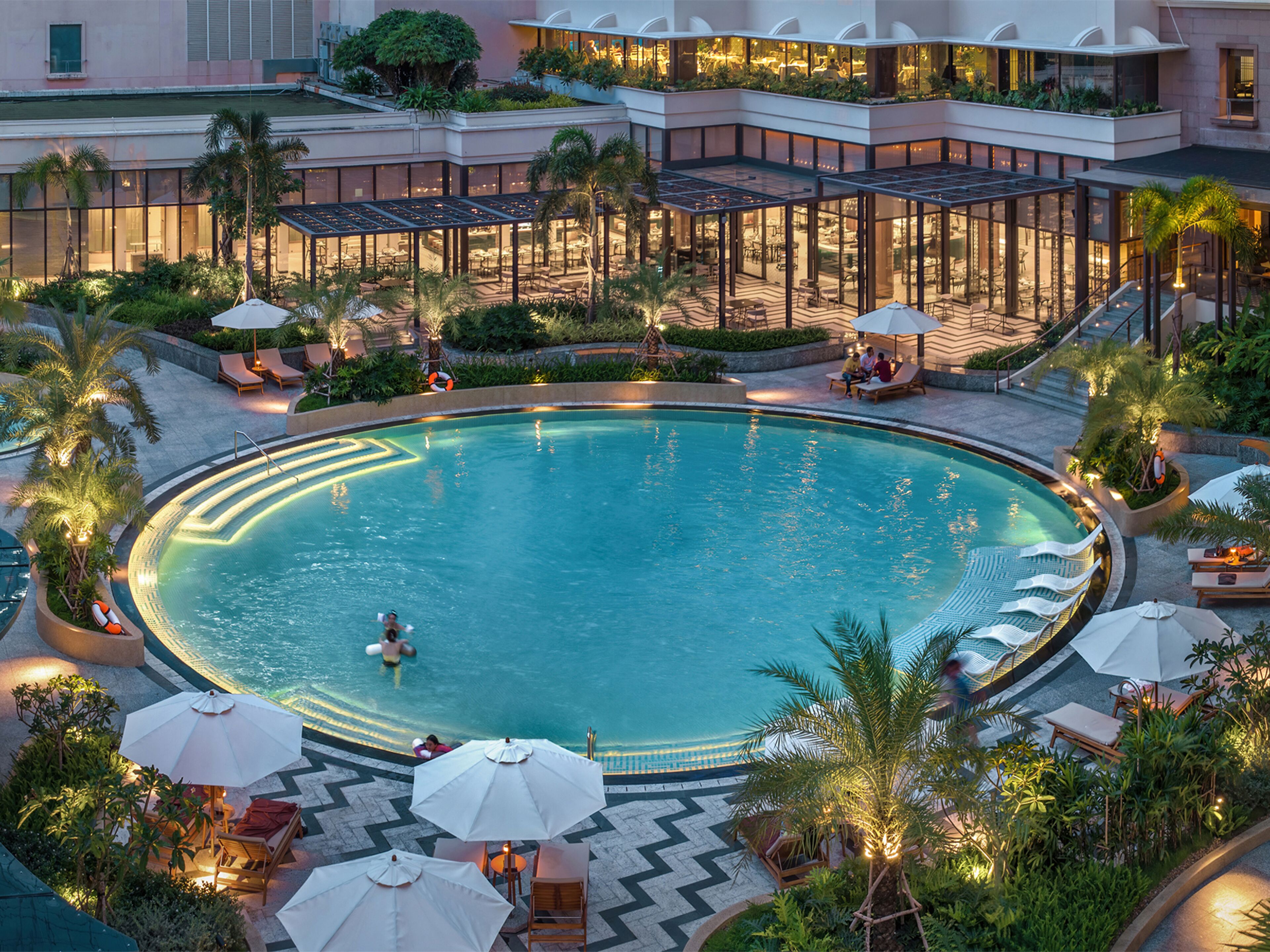 A large indoor swimming pool surrounded by lounge areas with umbrellas and seating.