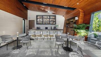 Zona de bar moderna con techo de madera, taburetes y una exhibición de botellas.