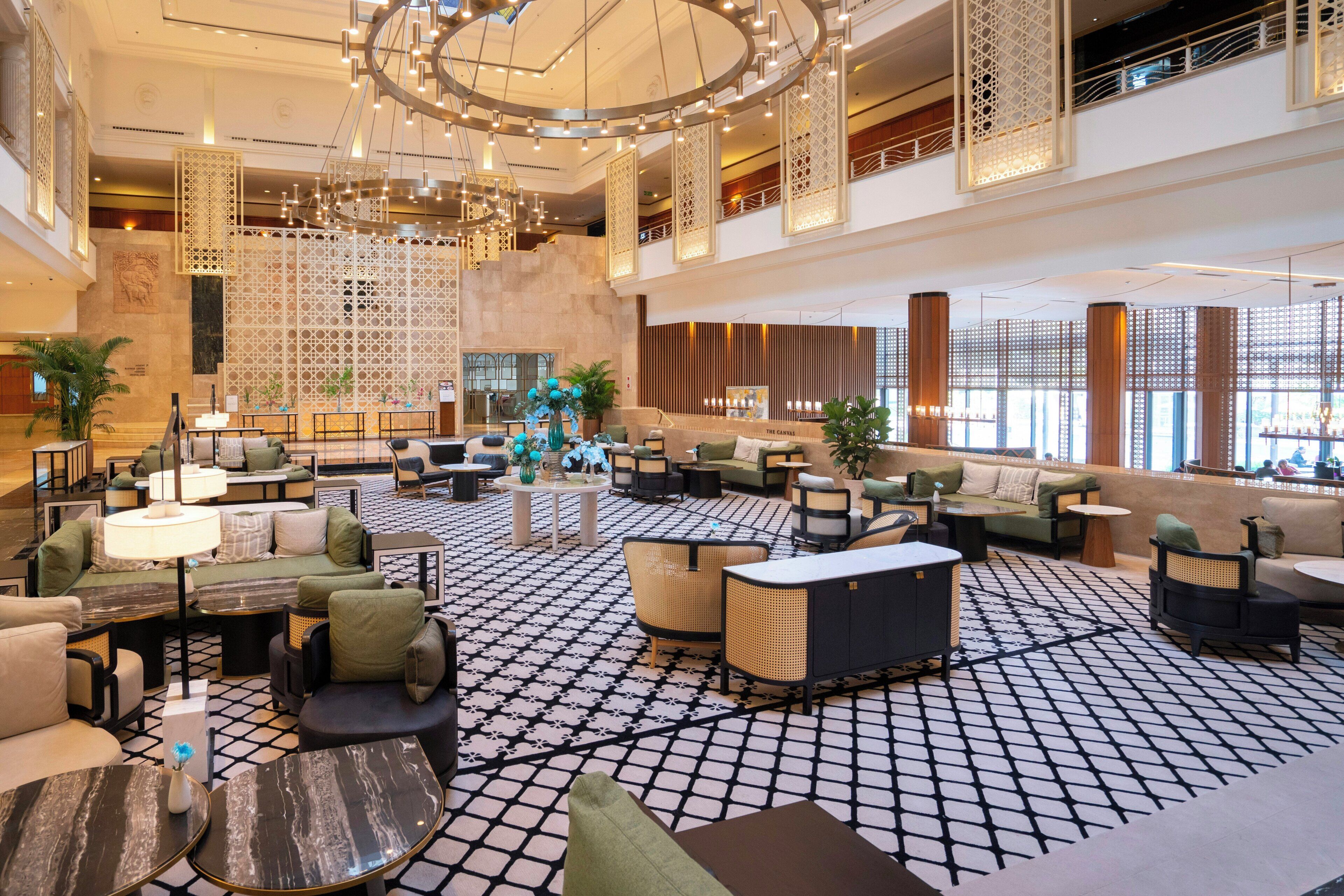 A spacious lobby with multiple seating areas, a patterned floor, and decorative lighting fixtures.