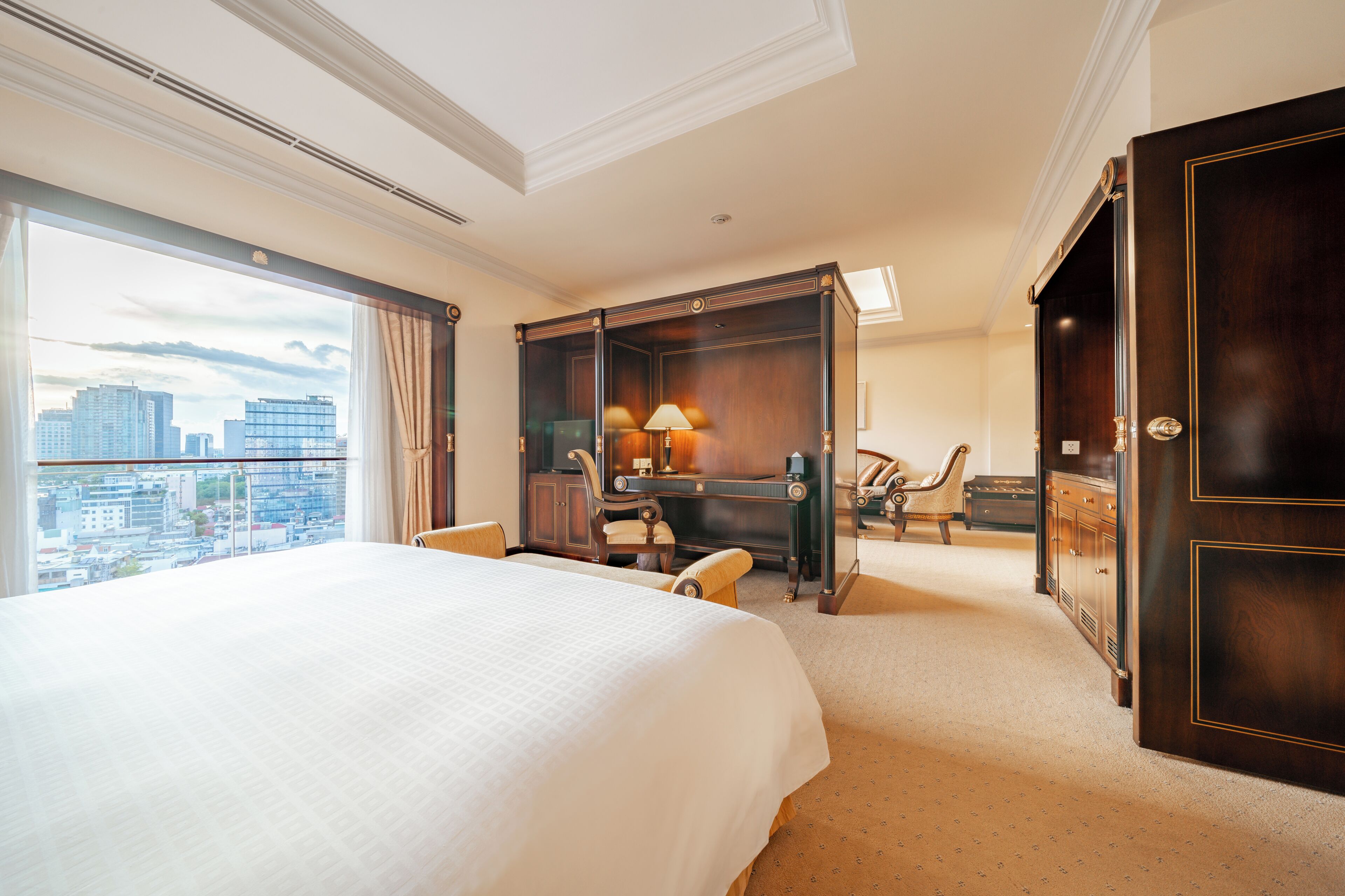 Une chambre d’hôtel avec un grand lit, un bureau, une chaise, une armoire et une vue sur la ville.