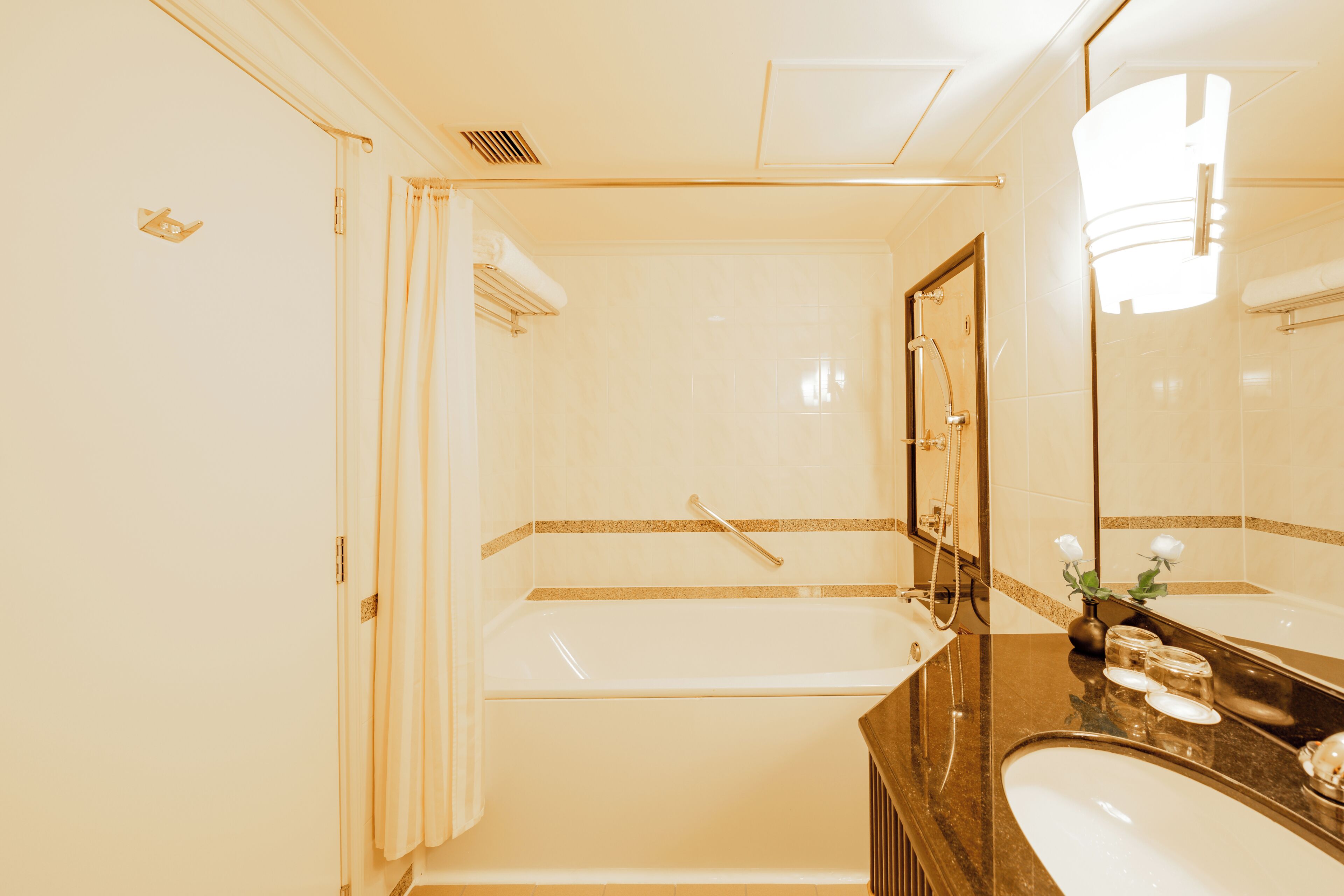 A bathroom with a bathtub, a sink, and a mirror.