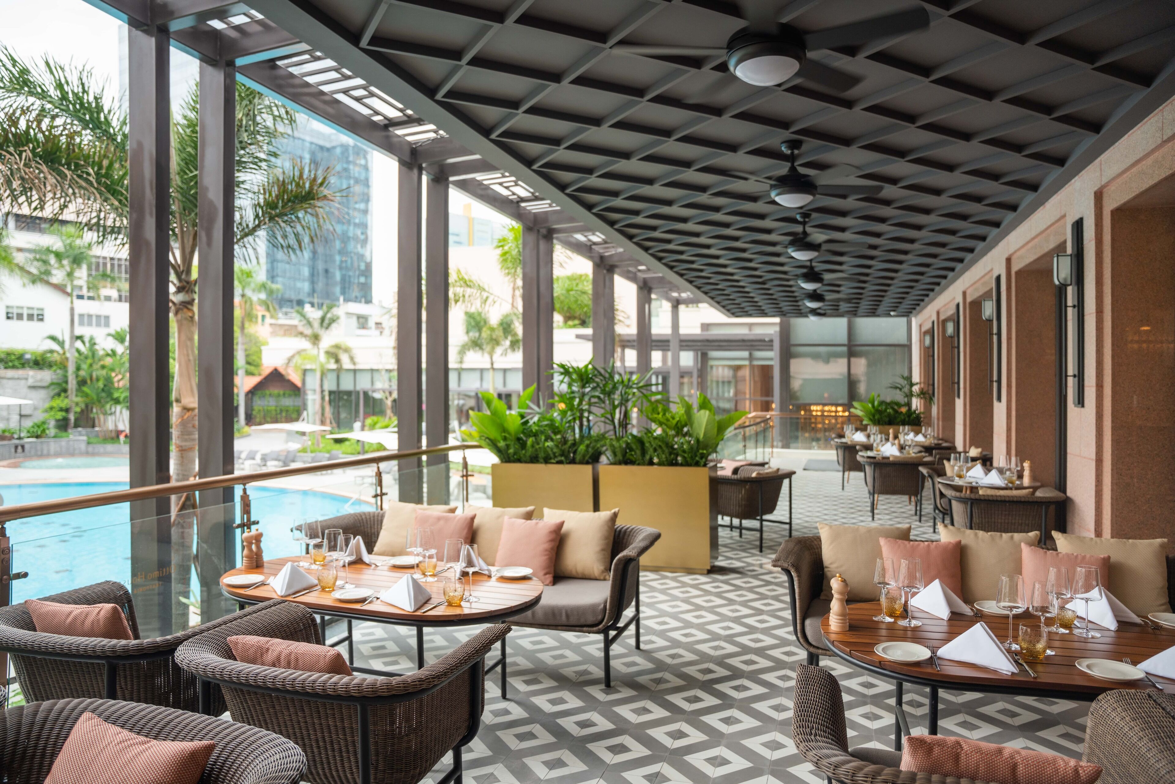 A rooftop restaurant with outdoor seating, a pool, and a view of the cityscape.