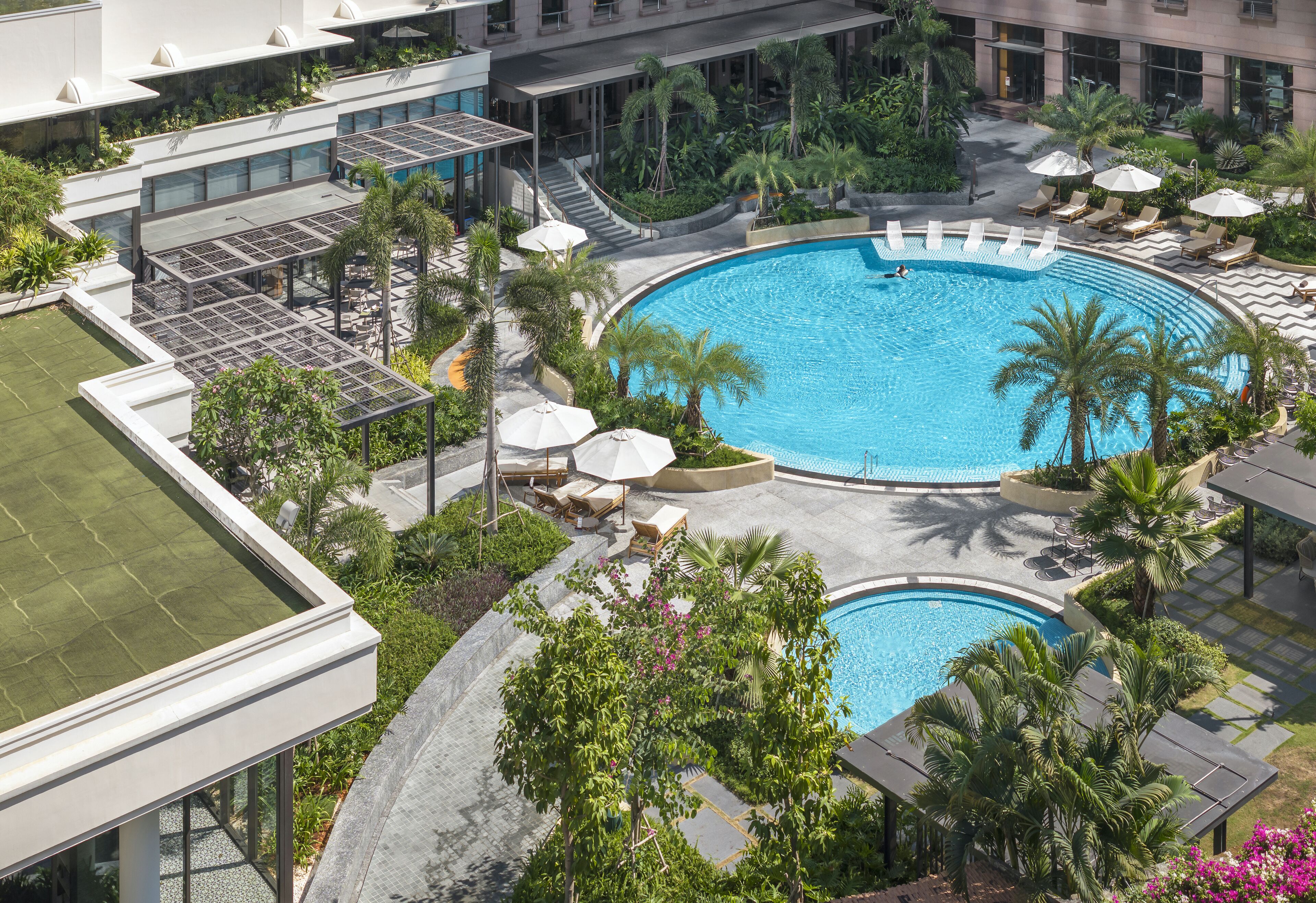 Et tagområde med swimmingpools, liggestole og palmer.