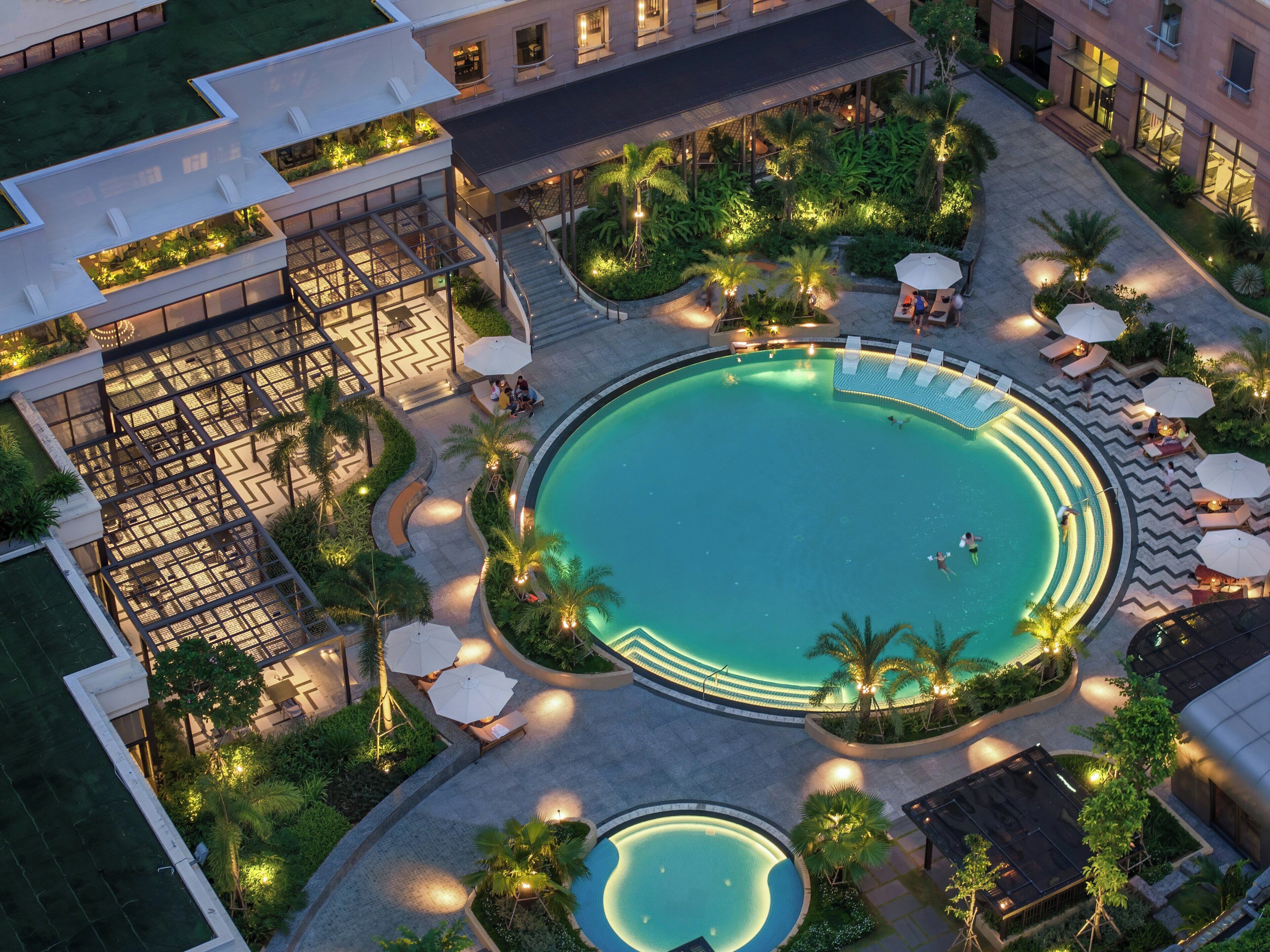 Un área de piscina en la azotea con piscina circular, sillas de descanso y sombrillas.