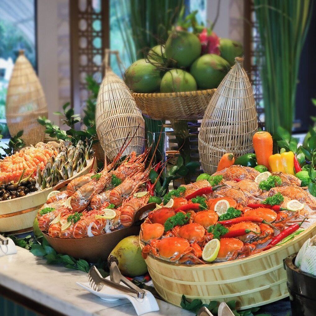 A buffet with seafood, including lobsters and shrimp, arranged on a table with decorative baskets and greenery.