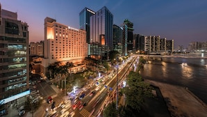 A cityscape with modern high-rise buildings, a river, and a busy street with moving vehicles. - Lotte Hotel Saigon (Ho Chi Minh City)