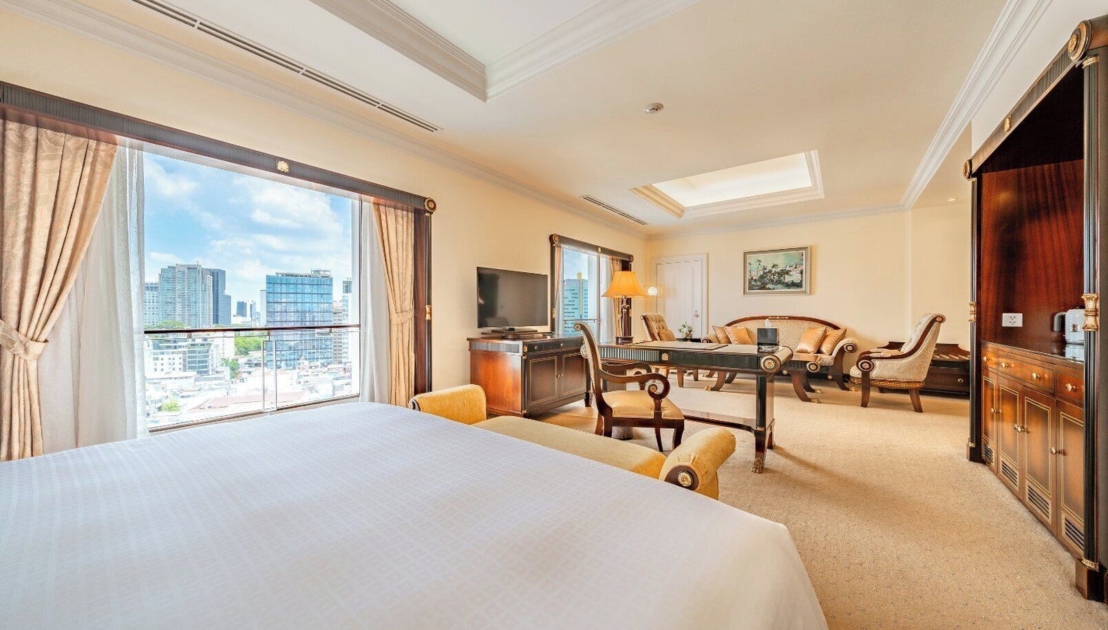 Habitación de hotel con una cama grande, un escritorio, televisión y vistas a la ciudad.