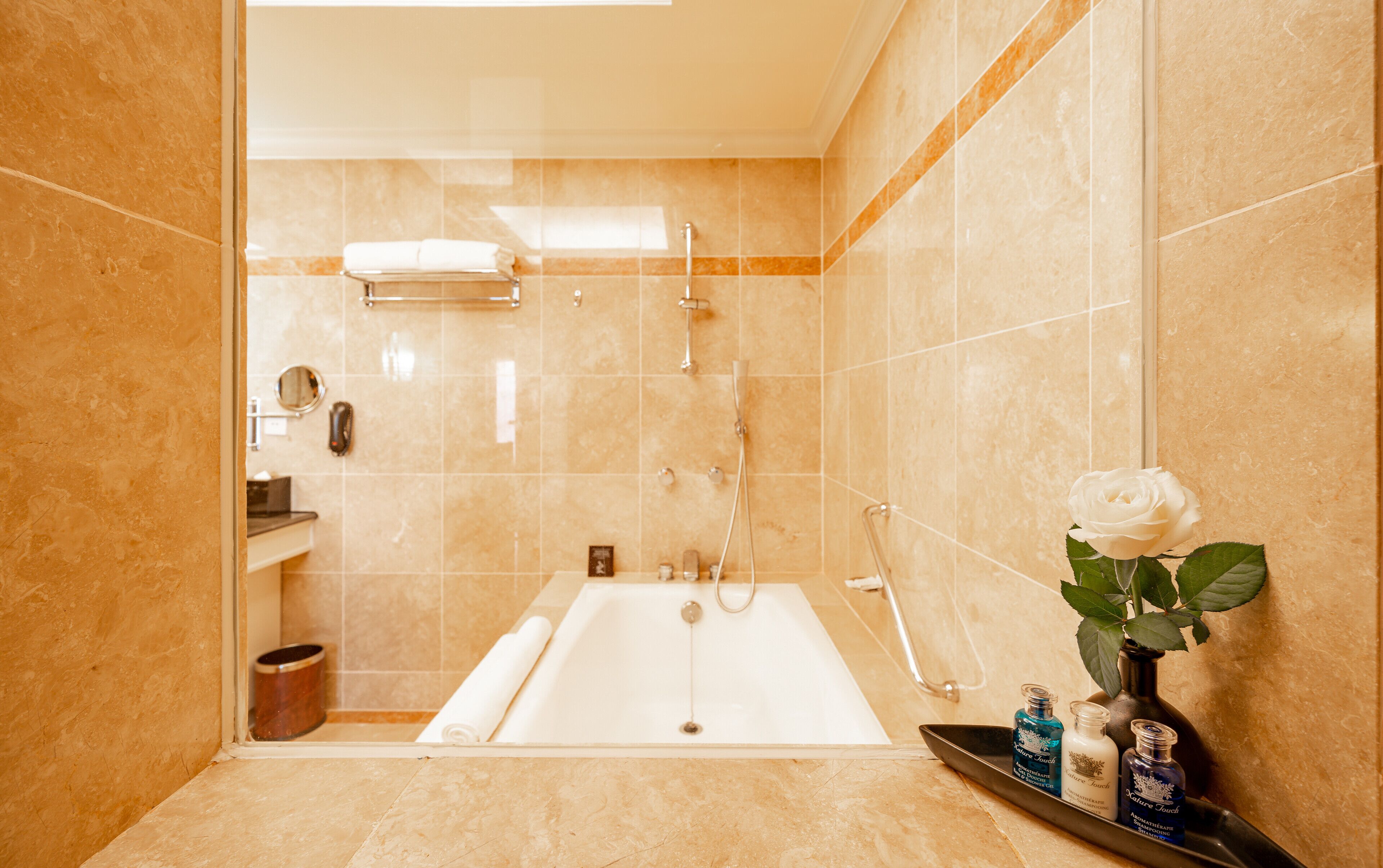 A bathroom with a bathtub, a shower, and a vanity with toiletries.