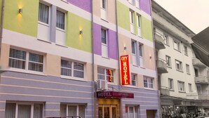 Een meerlaags hotel met een kleurrijke gevel, een opvallend 'HOTEL' bord en een duidelijke ingang.