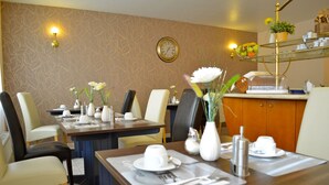 Een restaurantgedeelte in een hotel, met twee ontbijttafels, voorzien van witte bekers, borden en bestek.