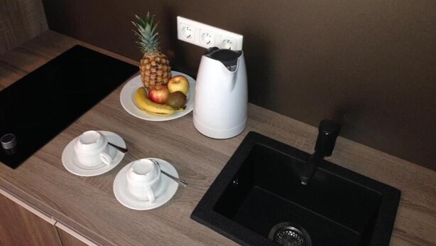 Een aanrecht met een koffiezetapparaat, een schaal fruit en twee kopjes.