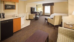 Une chambre d’hôtel équipée d’une kitchenette, d’un lit, d’un bureau et de deux chaises.