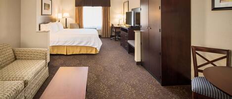 A hotel room with a bed, a desk, a chair, a sofa, and a television.
