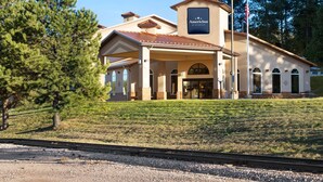 Un hôtel doté d’une entrée couverte, d’un mât et d’une enseigne indiquant qu’il s’agit d’un établissement de la chaîne AmericInn, appartenant au groupe Wyndham.
