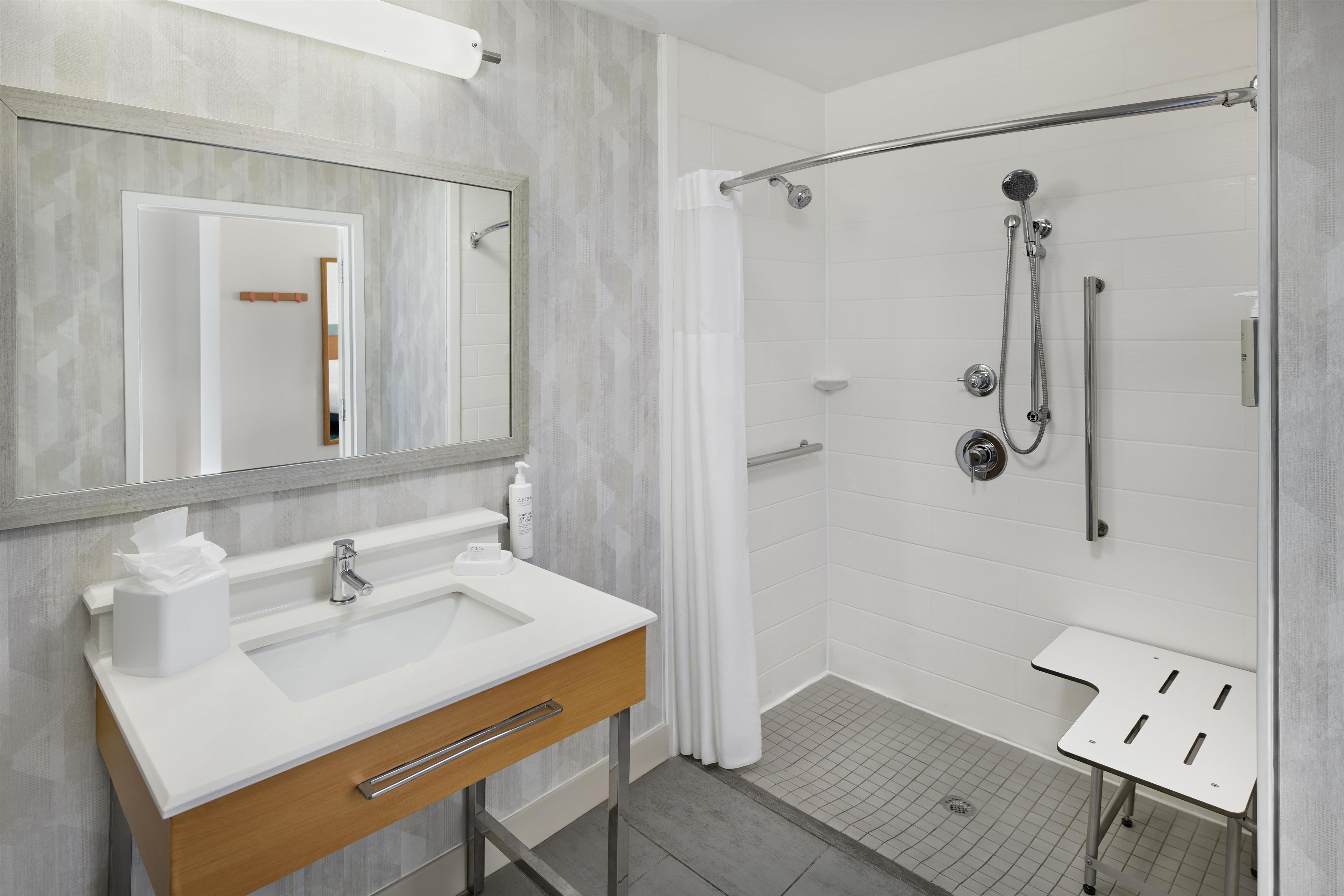 Un baño moderno con lavamanos blanco, espejo y zona de ducha.