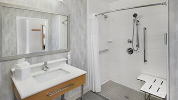 Un baño moderno con lavamanos blanco, espejo y zona de ducha.