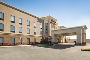 A hotel with a beige facade, multiple windows, and a sign reading "Hampton Inn & Suites".