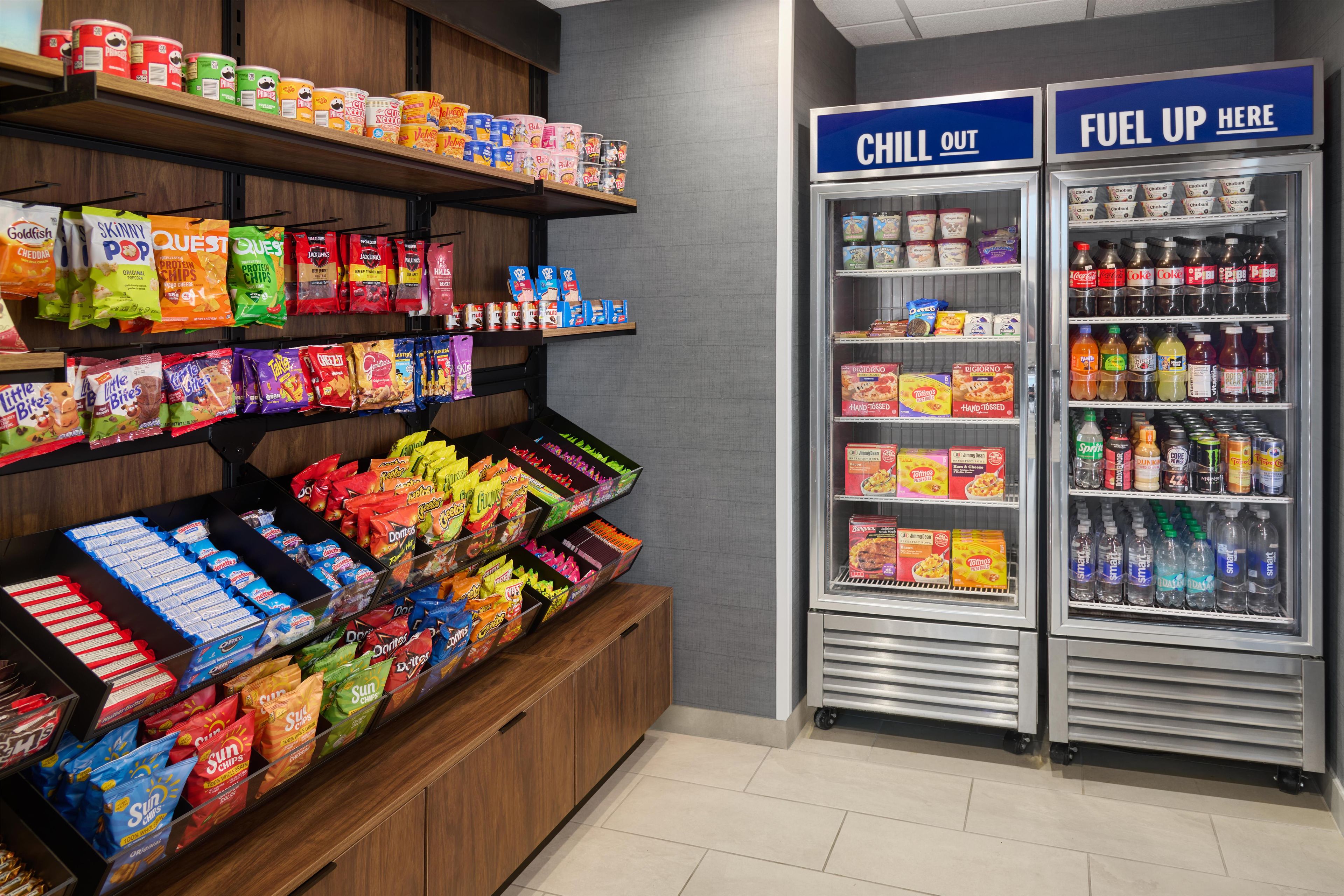Pasillo con diversas papas fritas y snacks, una sección de bebidas frías y un área para reponer energías con bebidas.