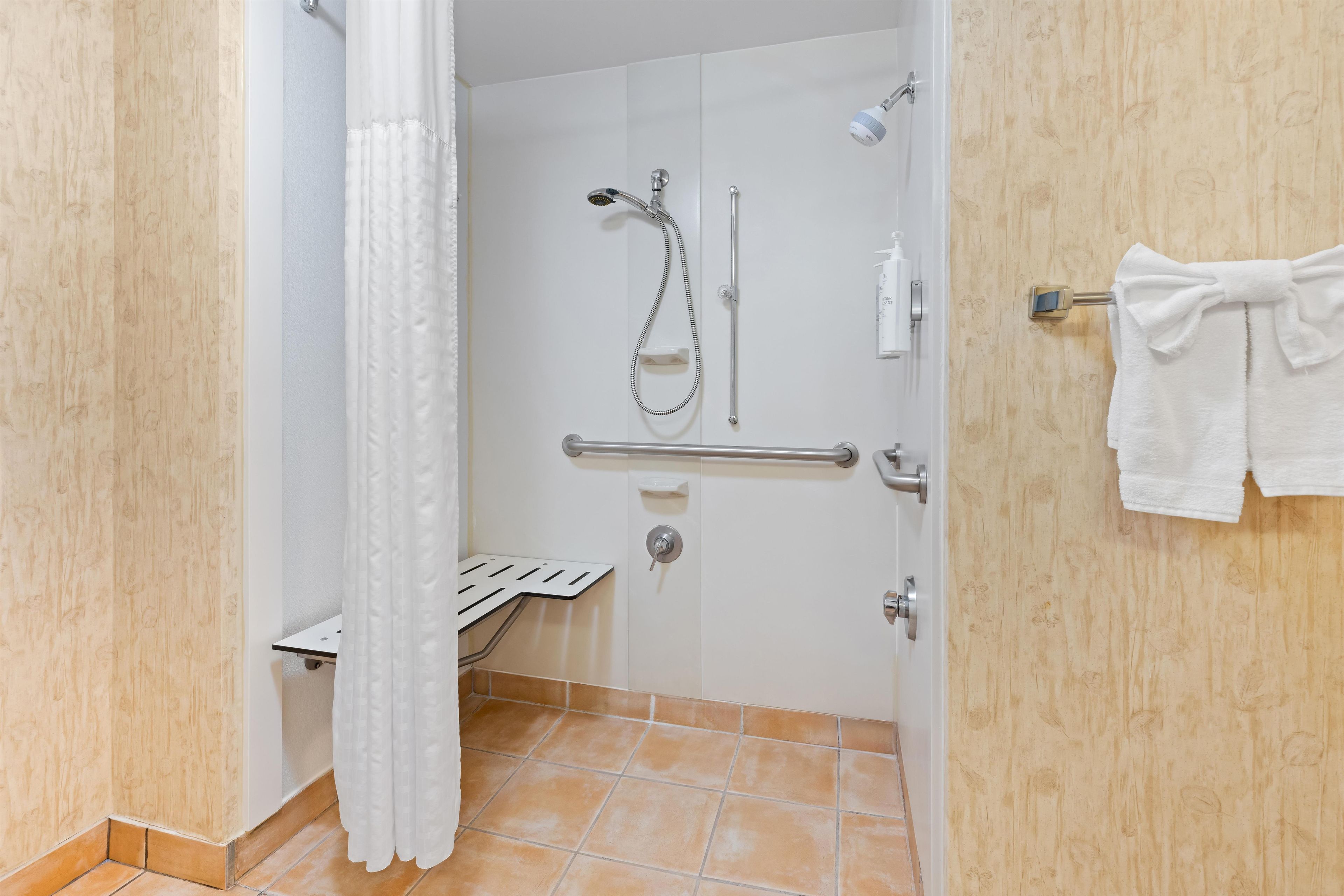 Un baño con ducha, inodoro y toallero.
