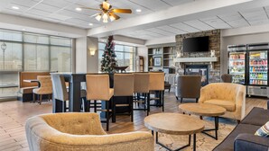 A hotel lobby with a dining area, seating, a fireplace, and a refrigerator stocked with beverages. - Hampton Inn Guntersville (Guntersville)
