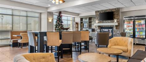 Vestíbulo de hotel con asientos, un árbol de Navidad, chimenea y televisor.