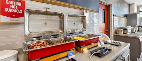 A buffet area with labeled food stations including maple sausage, scrambled eggs, and redskin potatoes.