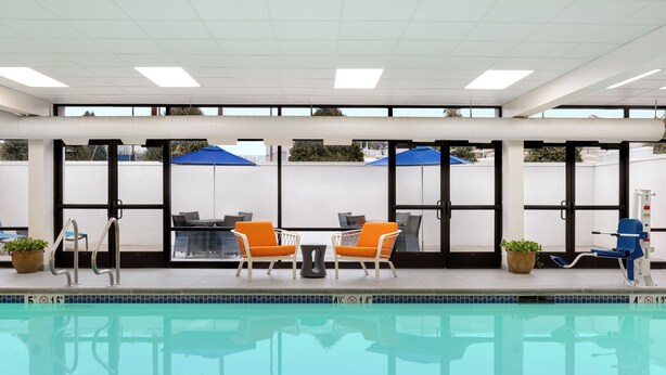 A swimming pool area with lounge chairs, umbrellas, and a lifeguard stand. - Hampton Inn Bloomsburg (Bloomsburg)