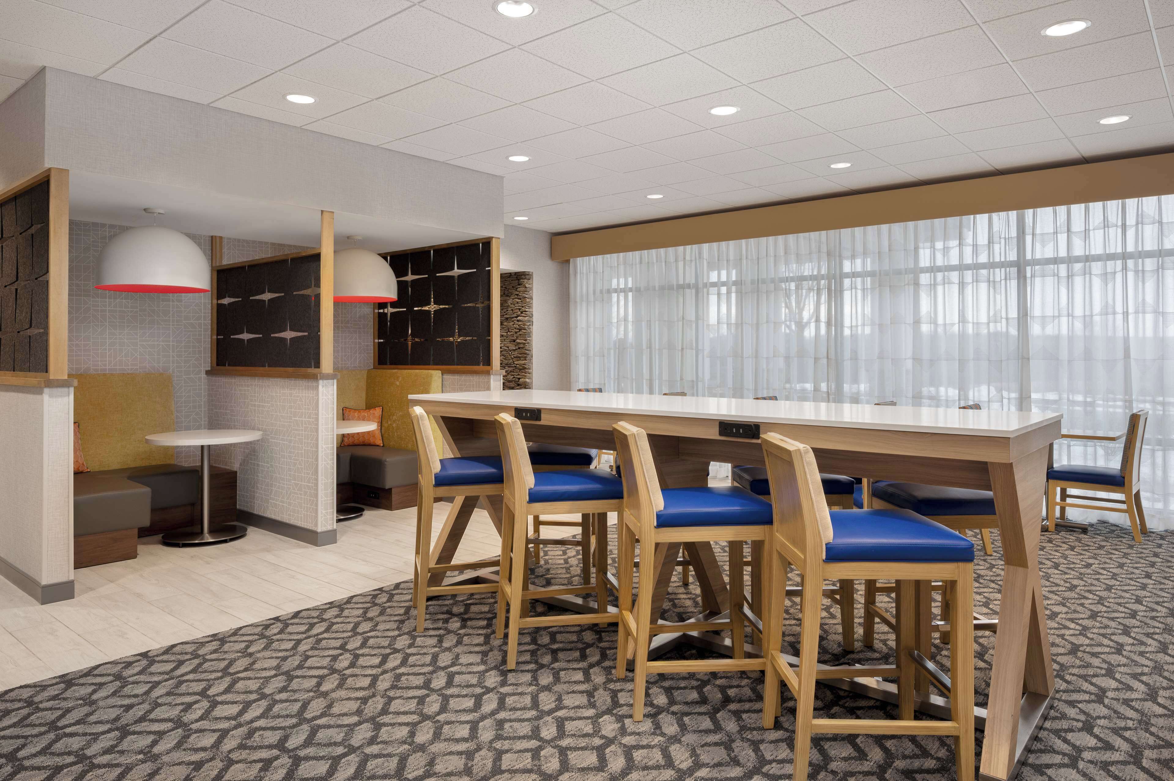 A modern conference room with a long table, blue cushioned chairs, and a patterned carpet.